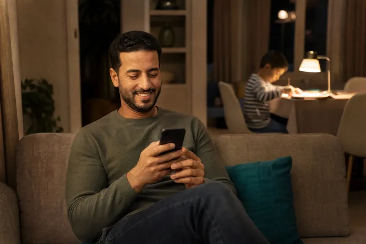 Papa consultant la scolarité de son fils sur son téléphone, le soir à la maison